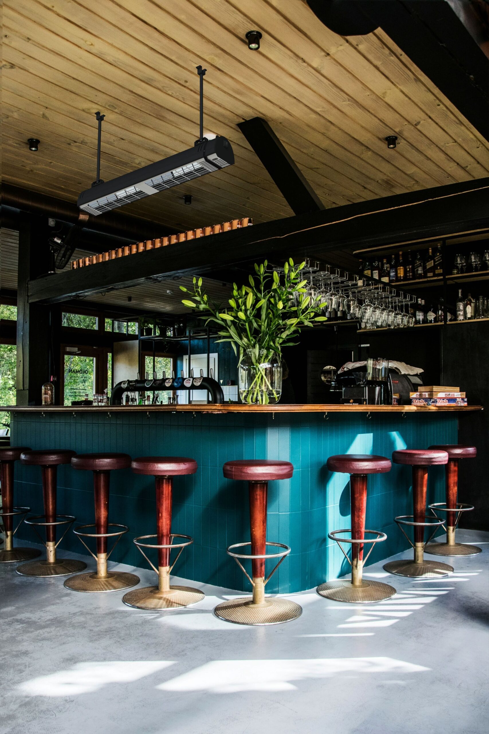 A semi-enclosed restaurant and bar with brown and gold bar stools, bar, and MEQ infrared heater with wooden rood.